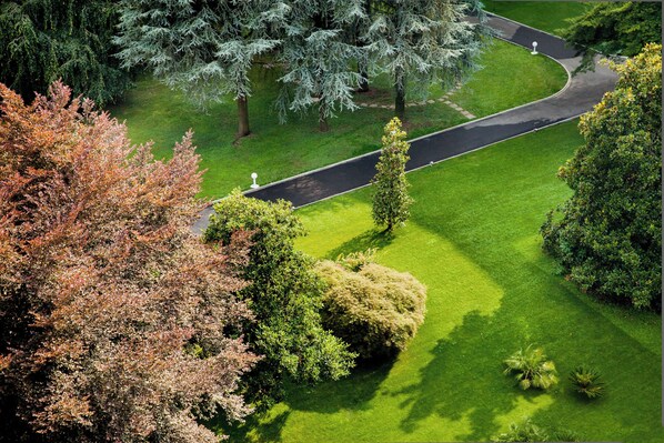 A landscaped garden with a winding path, neatly trimmed hedges, and mature trees.