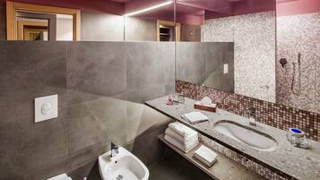 Un bagno moderno con uno specchio grande, un bidet, un lavandino e uno spazio doccia.