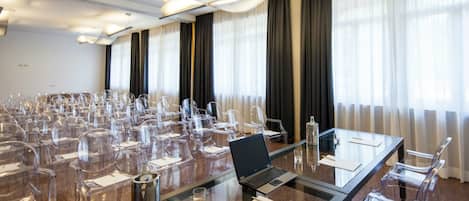 Un salón de conferencias con una larga mesa, sillas, una computadora portátil y un proyector.