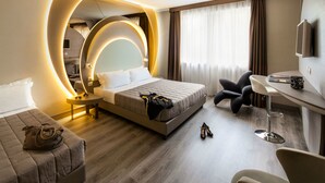 A modern hotel room with a large bed, a desk, a chair, and a television.
