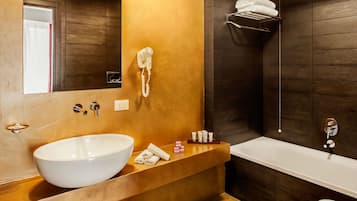 Un baño moderno con un lavamanos grande de color blanco, un secador de pelo incorporado, una bañera y un perchero para toallas.
