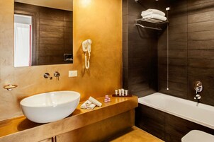 Een moderne badkamer met een groot wit wastafelmeubel, een ingebouwde haardroger, een badkuip en een handdoekhouder.