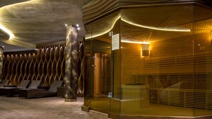 A modern lobby with a unique wavy ceiling design, a glass partition with a wooden panel, and a seating area with wicker furniture. - Hotel & SPA Diamant Residence - All Inclusive (Sunny Beach)