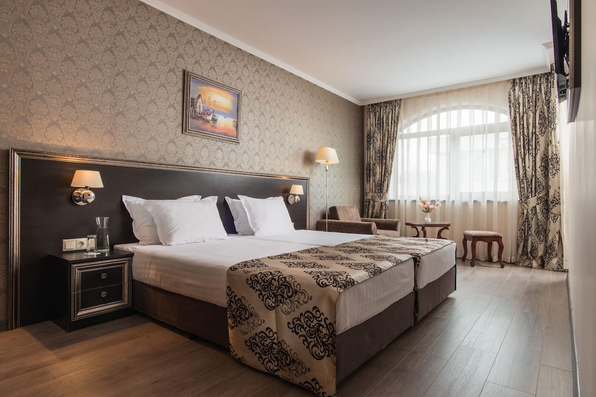 A hotel room with a large bed, bedside tables, a desk, and a chair.