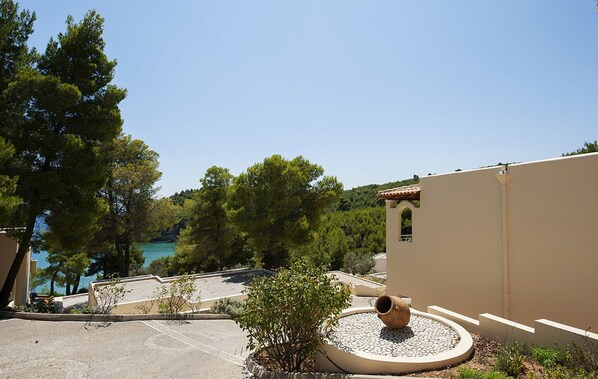 A coastal property with a parking area, a small garden with a decorative pot, and a view of the sea.