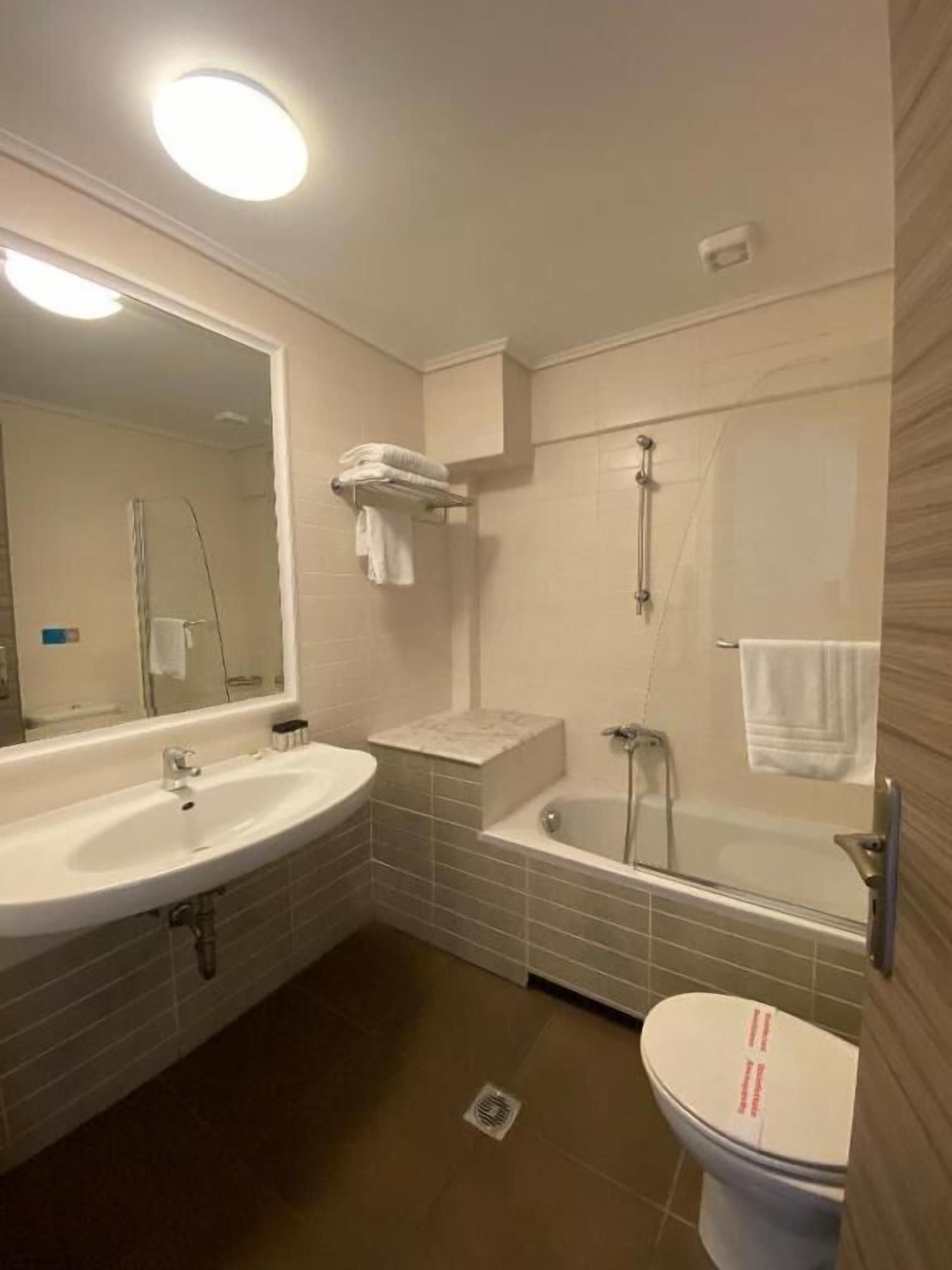 A modern bathroom with a sink, mirror, and bathtub.
