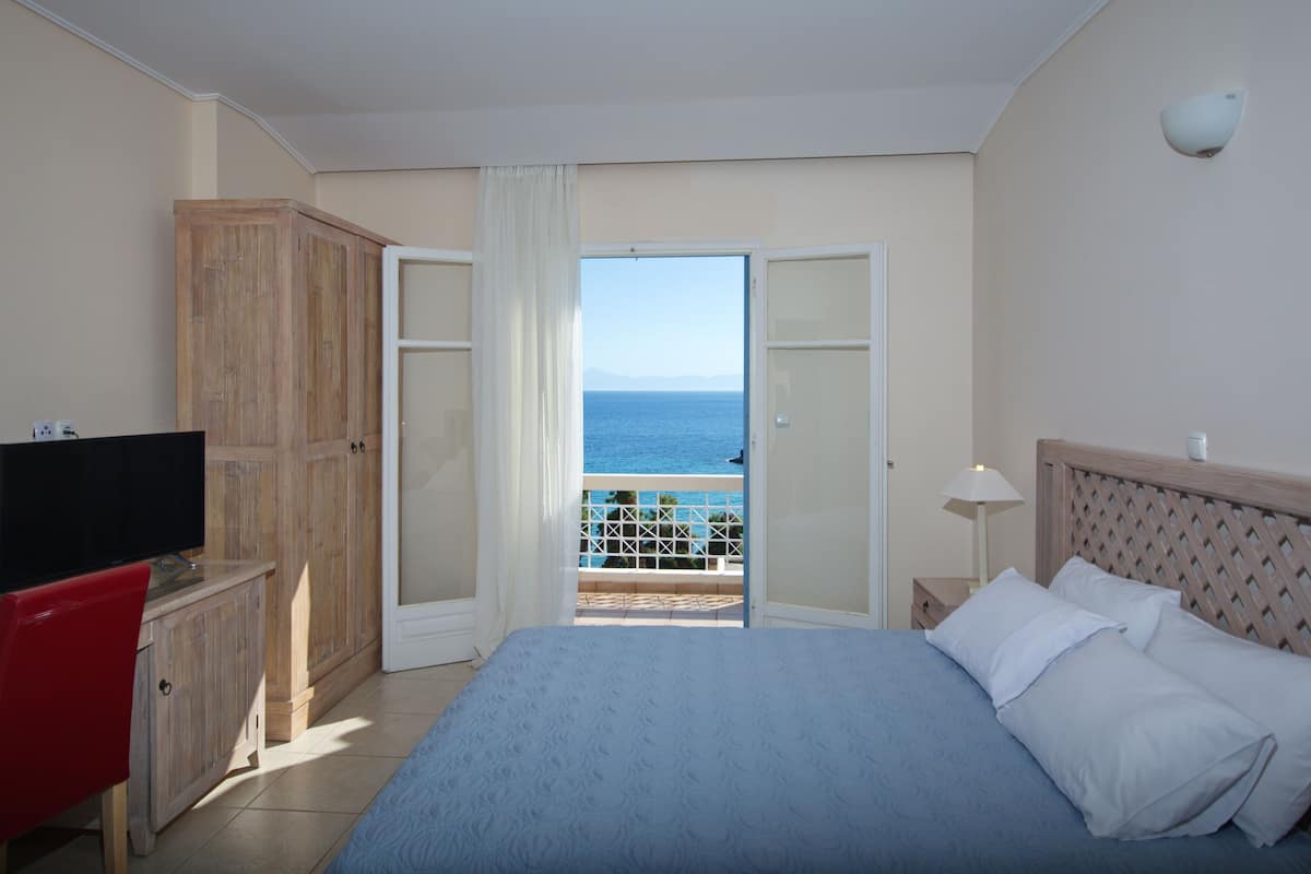 Ein Hotelzimmer mit Bett, Fernseher, Schreibtisch und Meerblick.