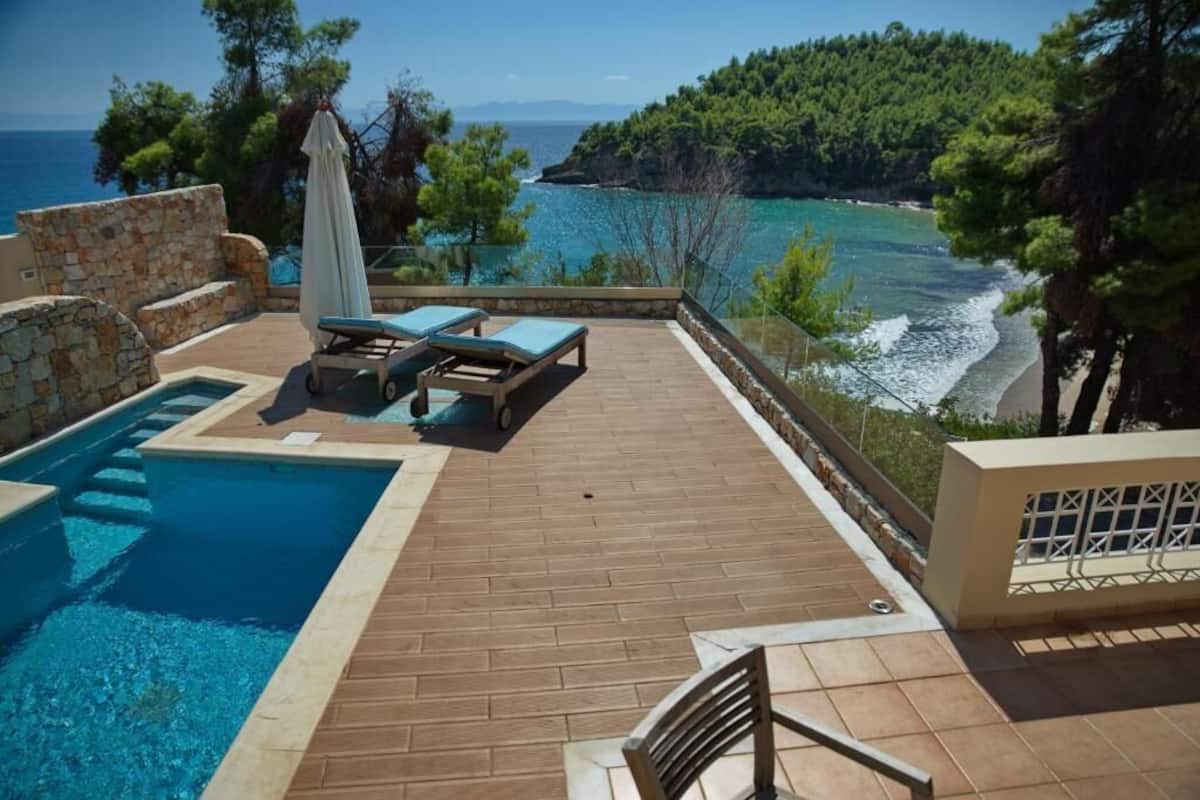 Ein Poolbereich mit Liegestühlen und Meerblick.