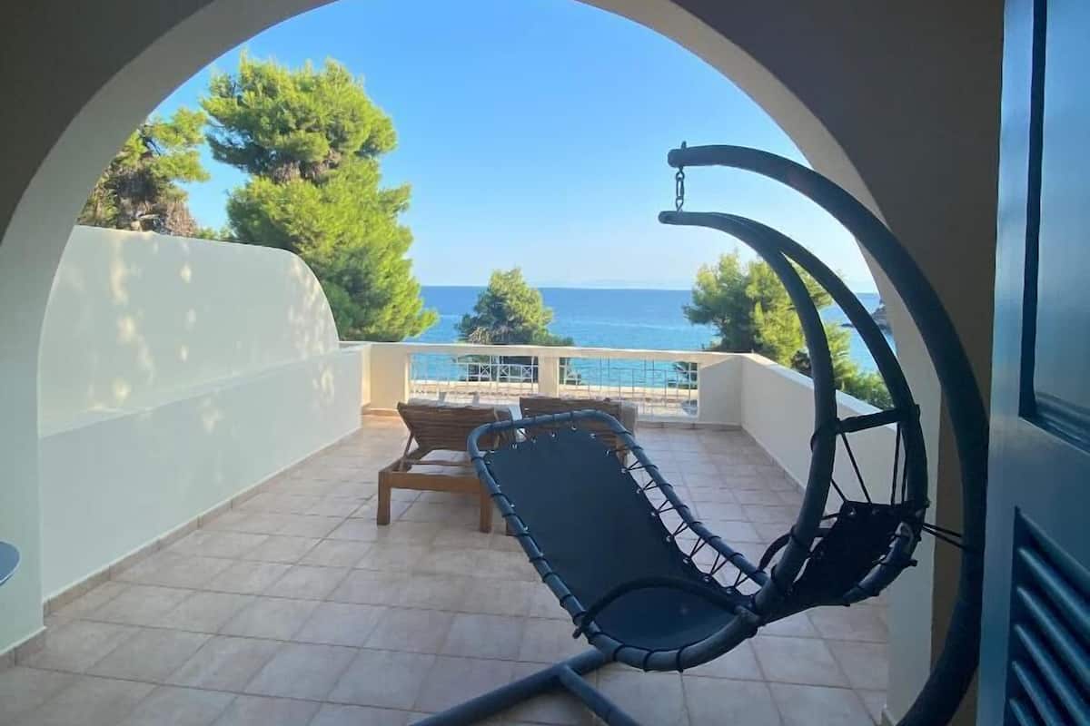 Ein Balkon mit einer Hängematten-Sitzgelegenheit, einem Tisch und Blick aufs Meer.