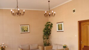 A living room with two sofas, a coffee table, a potted plant, and two chandeliers. - Apart-hotel Efir (Sunny Beach)