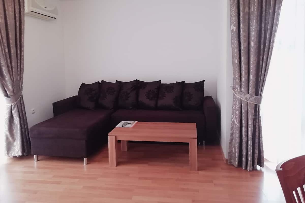 A living room with a dark-colored sofa, a wooden coffee table, and patterned curtains.