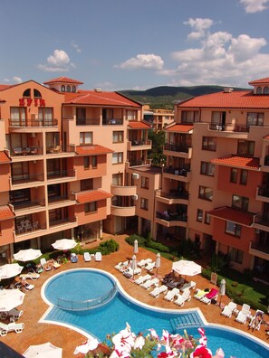 A multi-story hotel with a central swimming pool surrounded by sun loungers and umbrellas. - Apart-hotel Efir (Sunny Beach)
