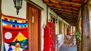 A hallway with a colorful mural, a red cabinet, and a hammock. - Pousada Estalagem Paraty (Paraty)