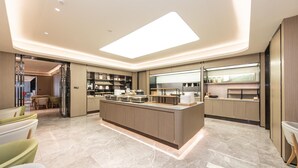 A modern kitchen with a central island, built-in appliances, and a dining area with chairs. - Ji Hotel (Shanghai)