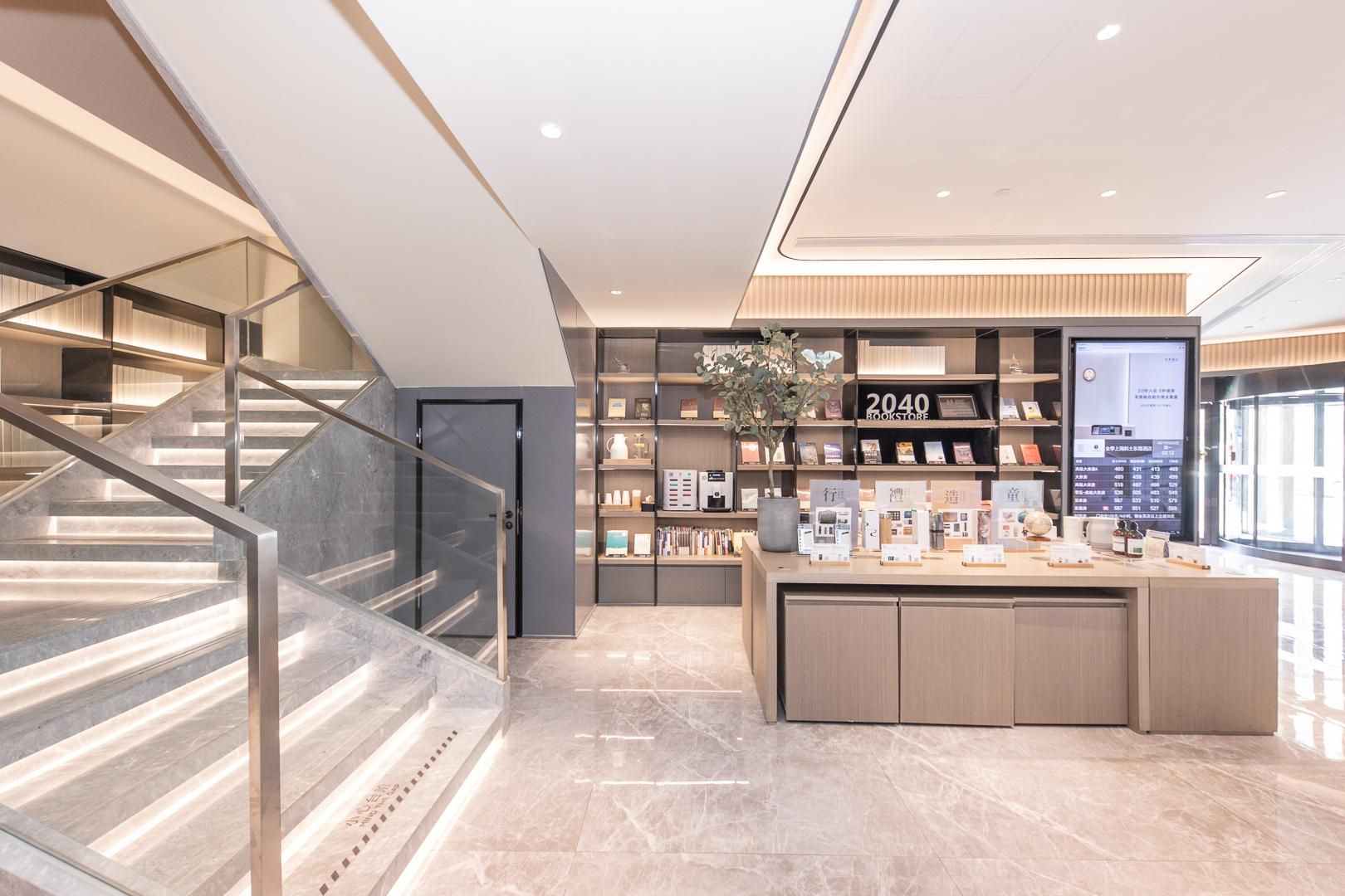 A modern bookstore interior with a staircase, marble flooring, and a digital display.