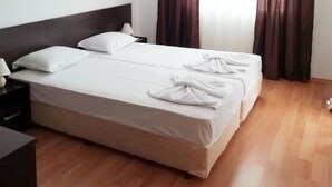 A hotel room with a double bed, a nightstand with a lamp, and a wooden floor. - Apart-hotel Happy (Sunny Beach)