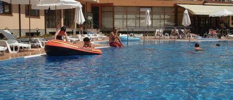 Una piscina al aire libre de temporada, sombrillas, tumbonas