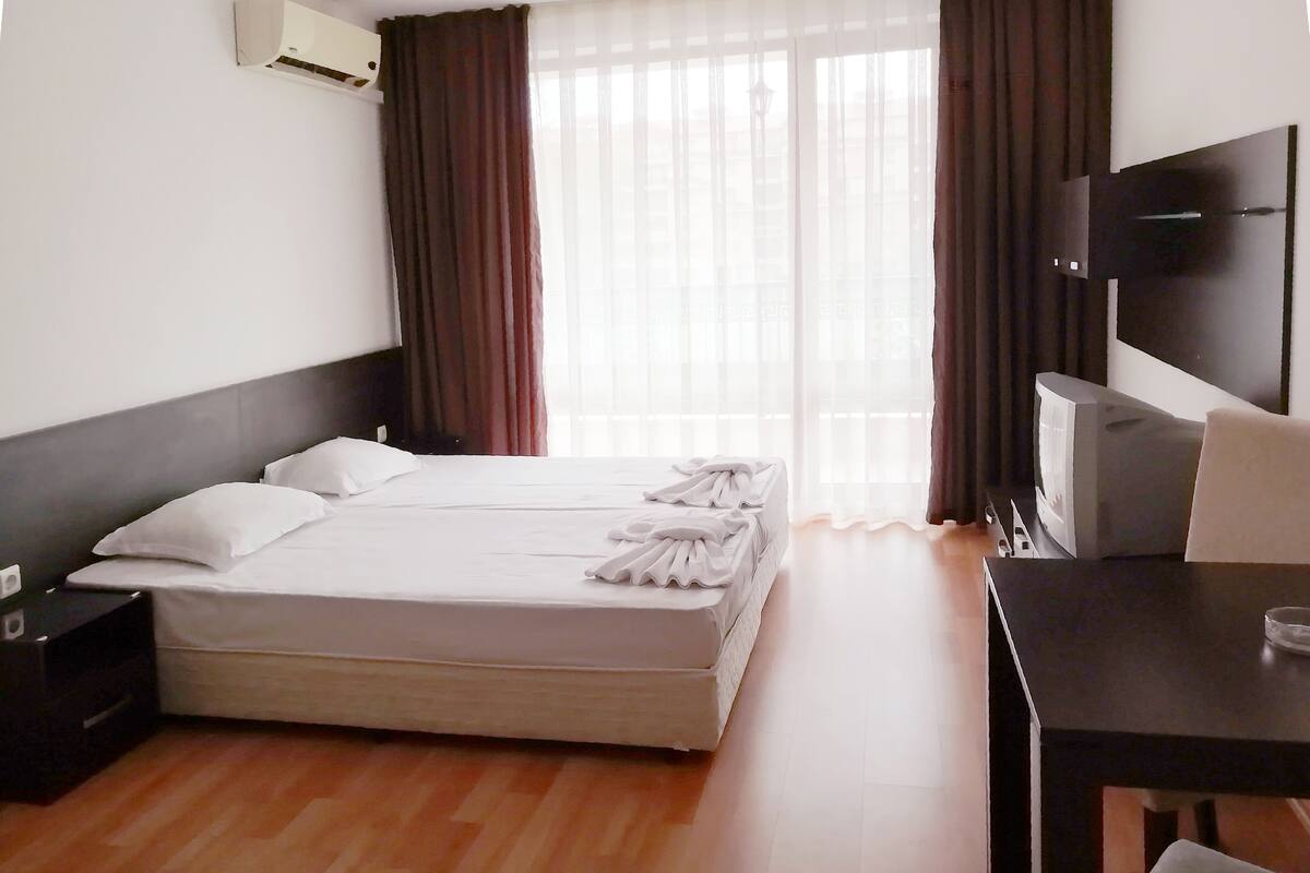 A hotel room with a bed, a desk, and a TV.