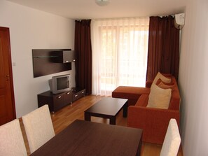 A living room with a TV, sofa, and coffee table. - Apart-hotel Happy (Sunny Beach)