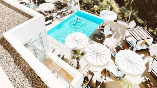 A rooftop pool with lounge chairs and umbrellas, surrounded by greenery and overlooking a coastal town. - Portals Hills Boutique Hotel (Calvia)