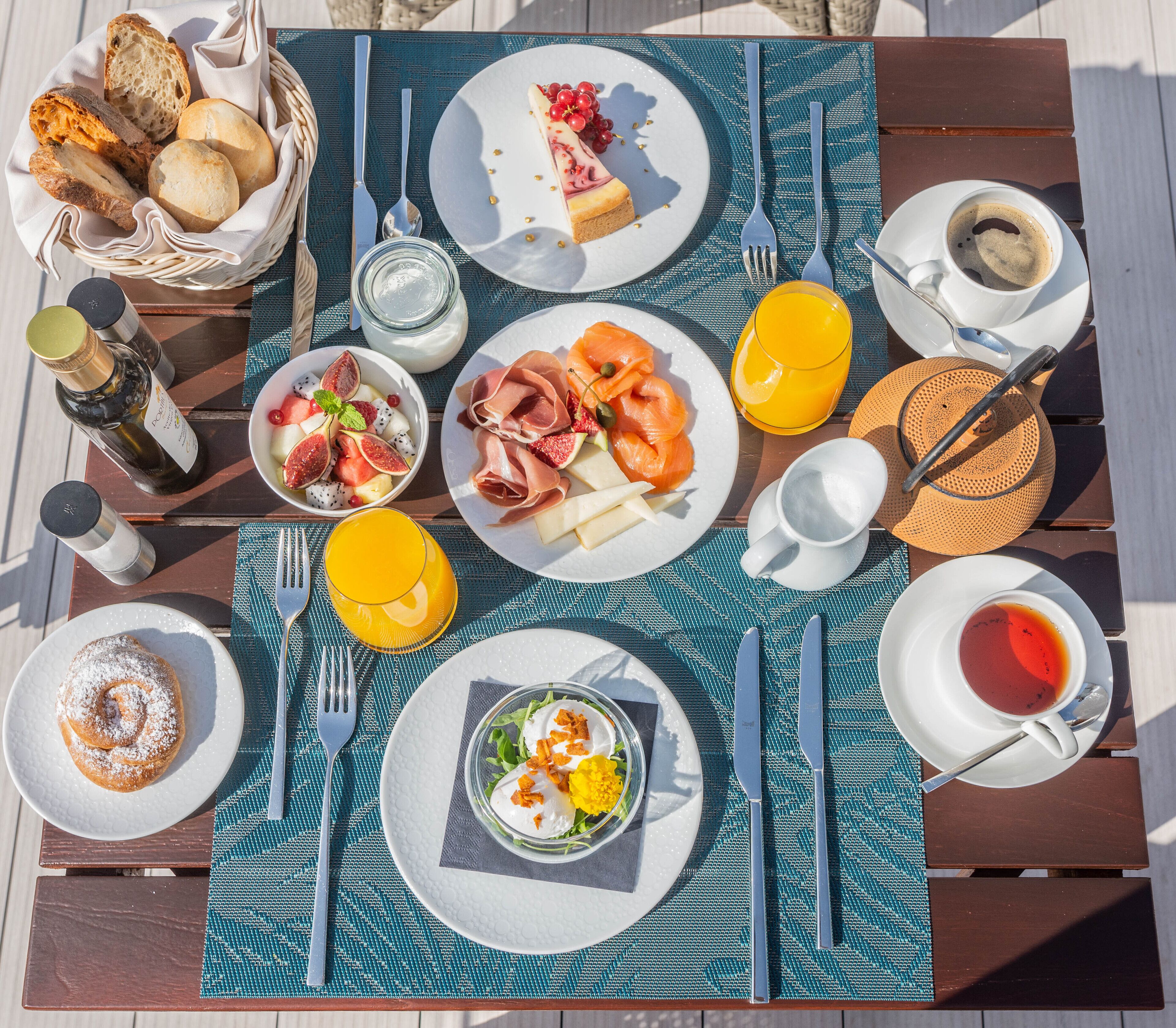 A breakfast table with various dishes, utensils, and drinks.