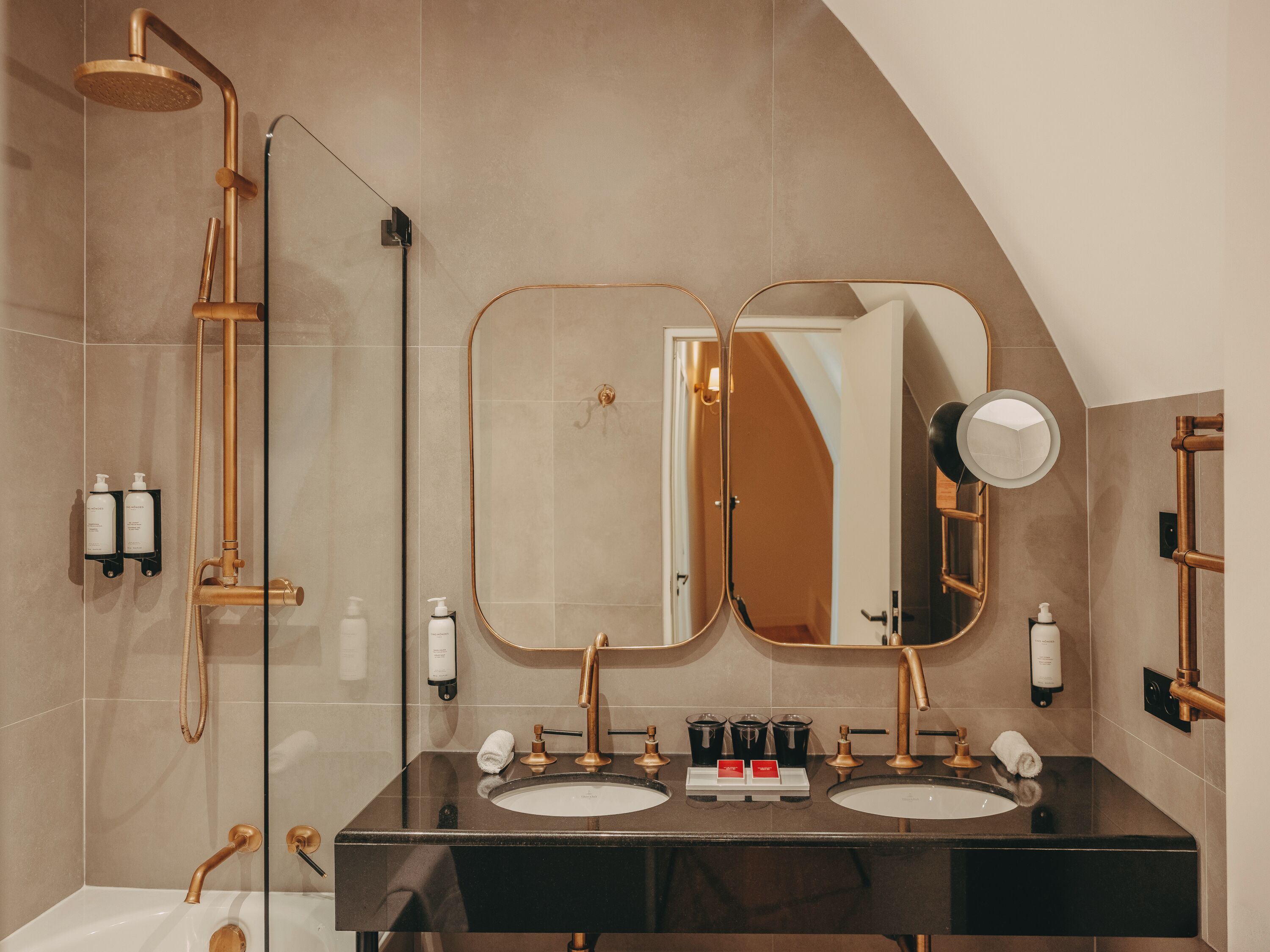 Een moderne badkamer met dubbele wastafels, een grote spiegel en een douche met een gouden kraan.