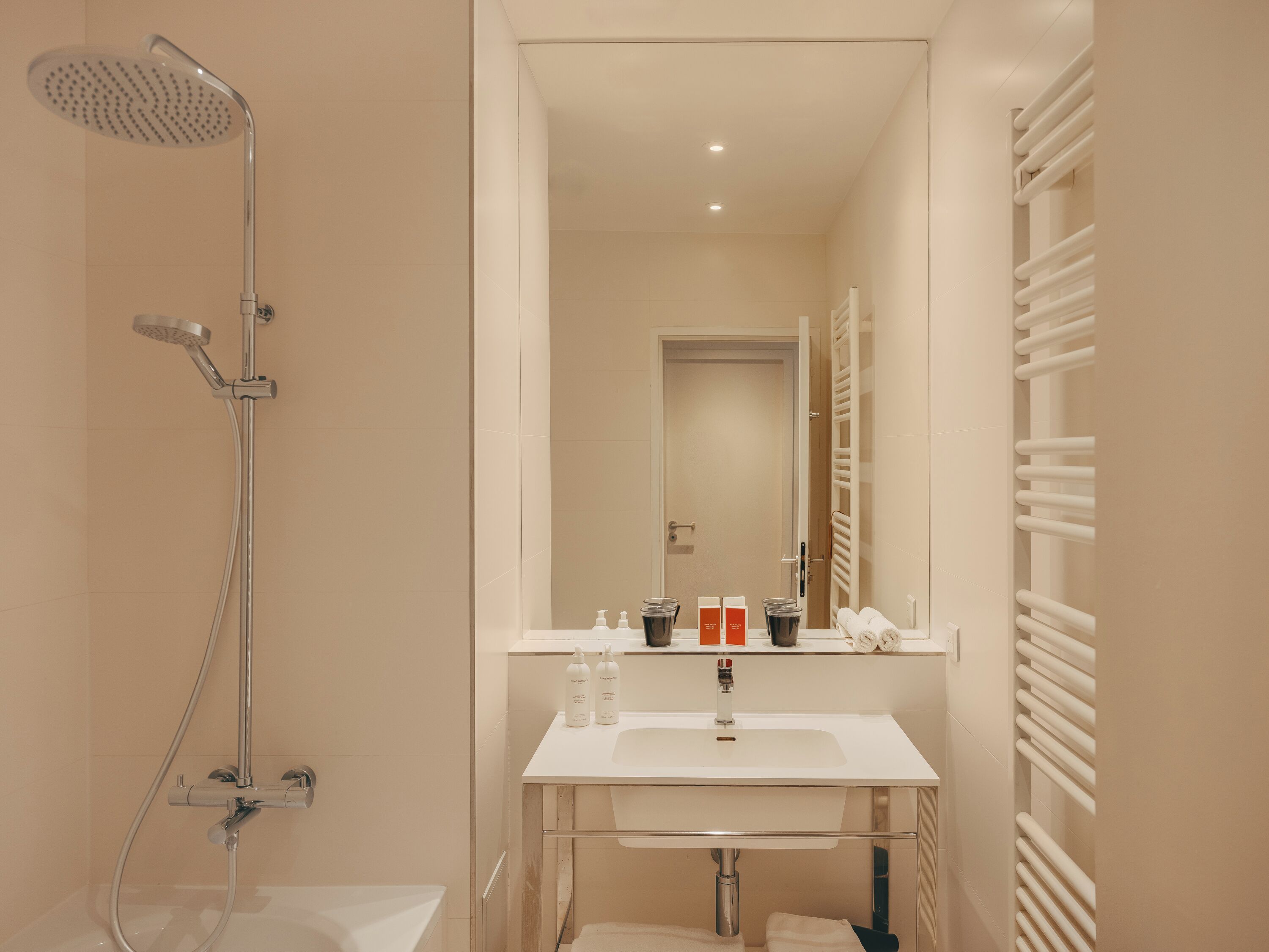 A modern bathroom with a shower, sink, and towel rack.