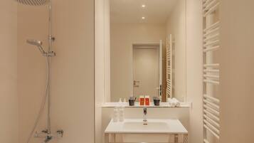 A modern bathroom with a shower, sink, and towel rack.