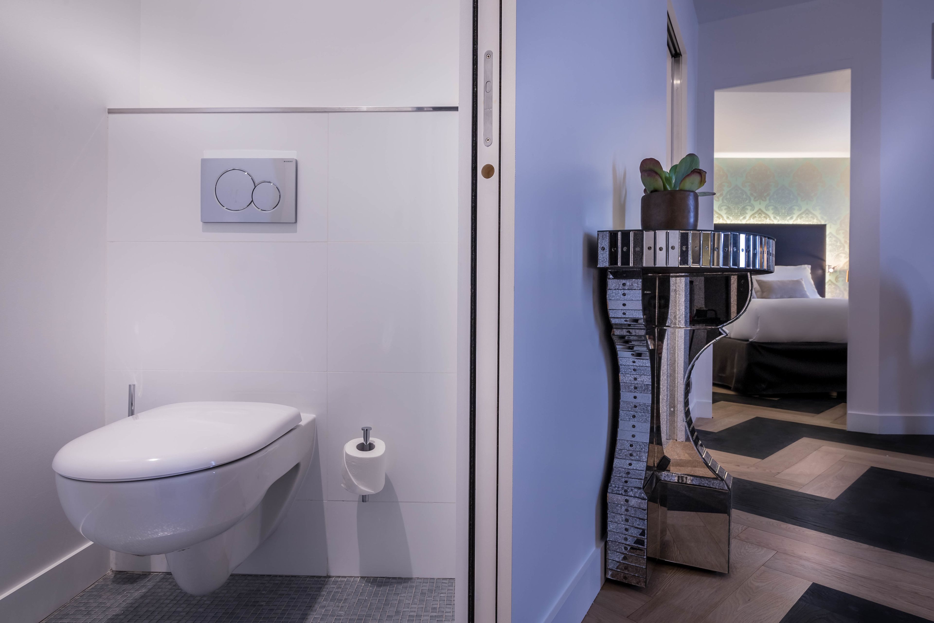 Ein modernes Badezimmer mit Toilette, Handtrockner und Toilettenpapierhalter an der Wand.