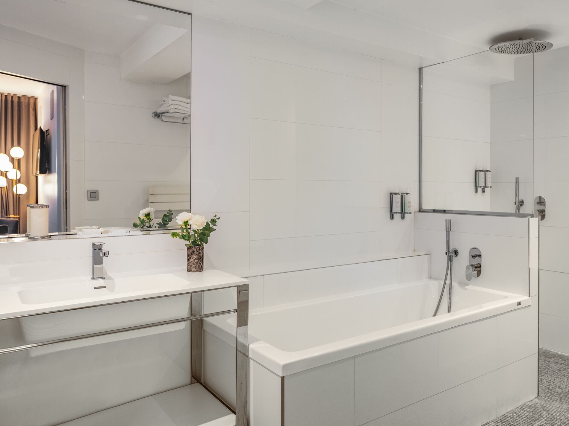 Une salle de bain moderne avec un grand miroir, des carreaux blancs, une baignoire et un espace douche.