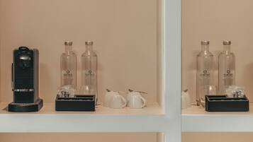 A hotel room with a minibar, two bottles of Castalie, a coffee maker, and a tea set.
