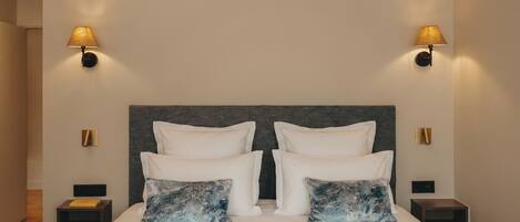 Une chambre d’hôtel avec un grand lit, deux tables de chevet et des lampes fixées au mur.