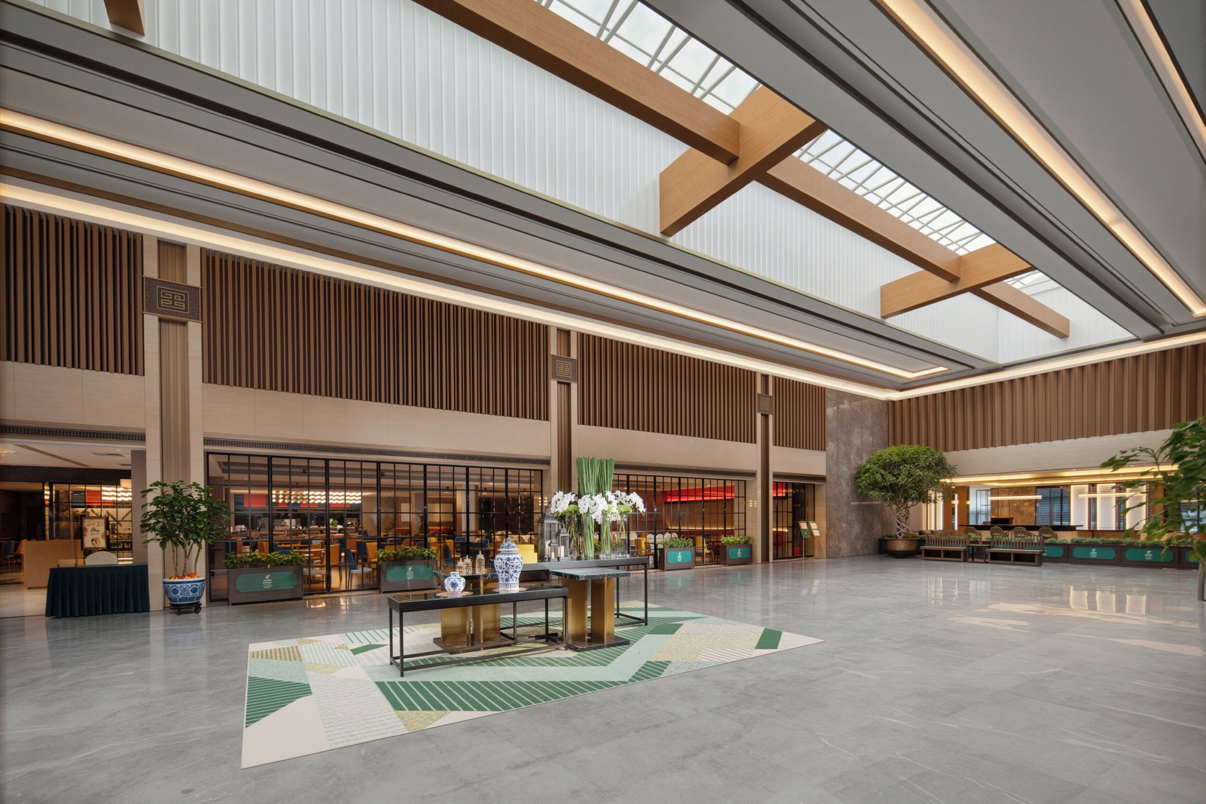 A spacious lobby with high ceilings, large windows, and a central seating area with a table and chairs.