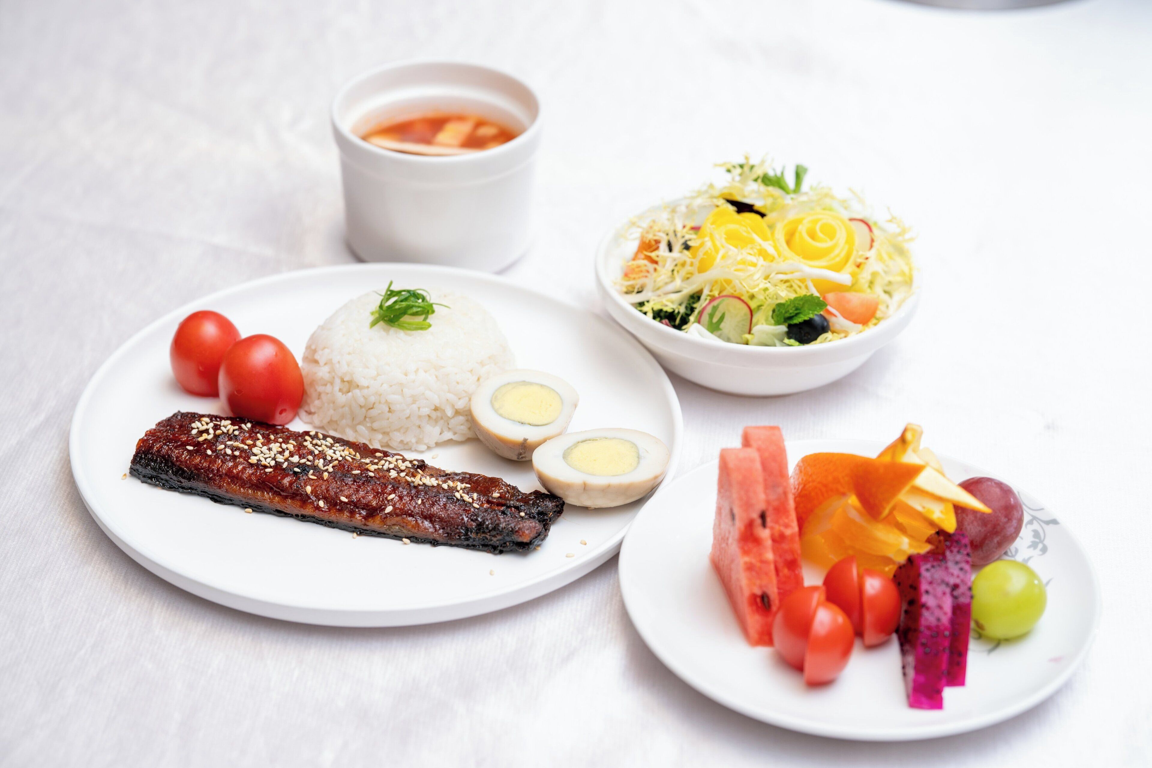 Ein Teller mit Reis, Fleisch, gekochten Eiern und einer Salat-Schüssel.