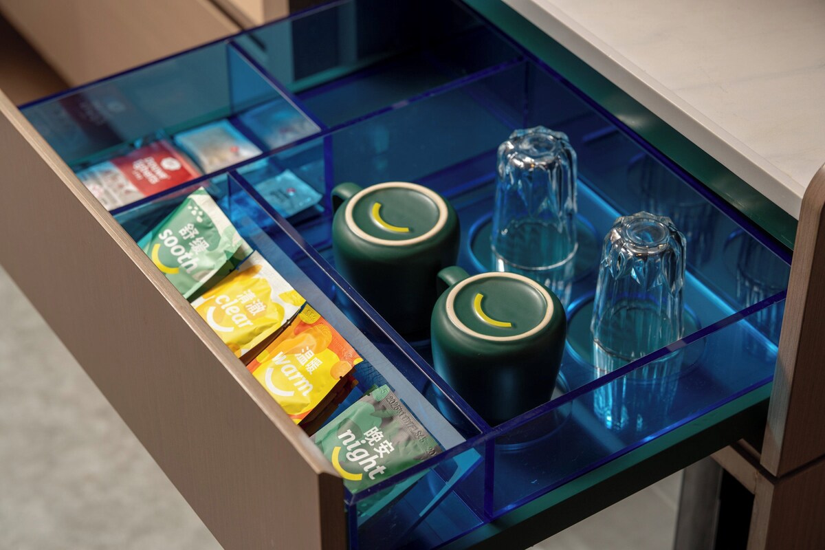 A minibar with tea bags, a green tea pot, and a glass pitcher.
