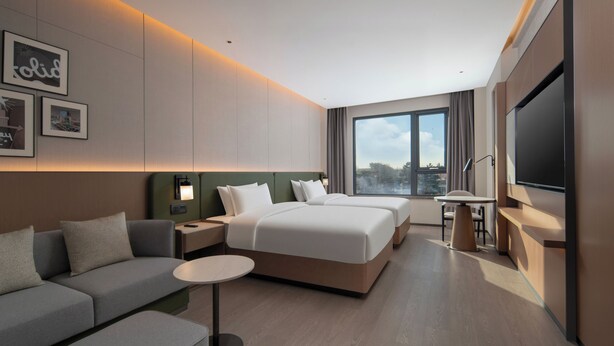 A modern hotel room with a large bed, a sofa, a desk, and a TV. - Holiday Inn Beijing Daxing Movie Park by IHG (Daxing)