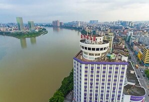 A high-rise hotel with a circular top, located near a river, surrounded by other buildings.