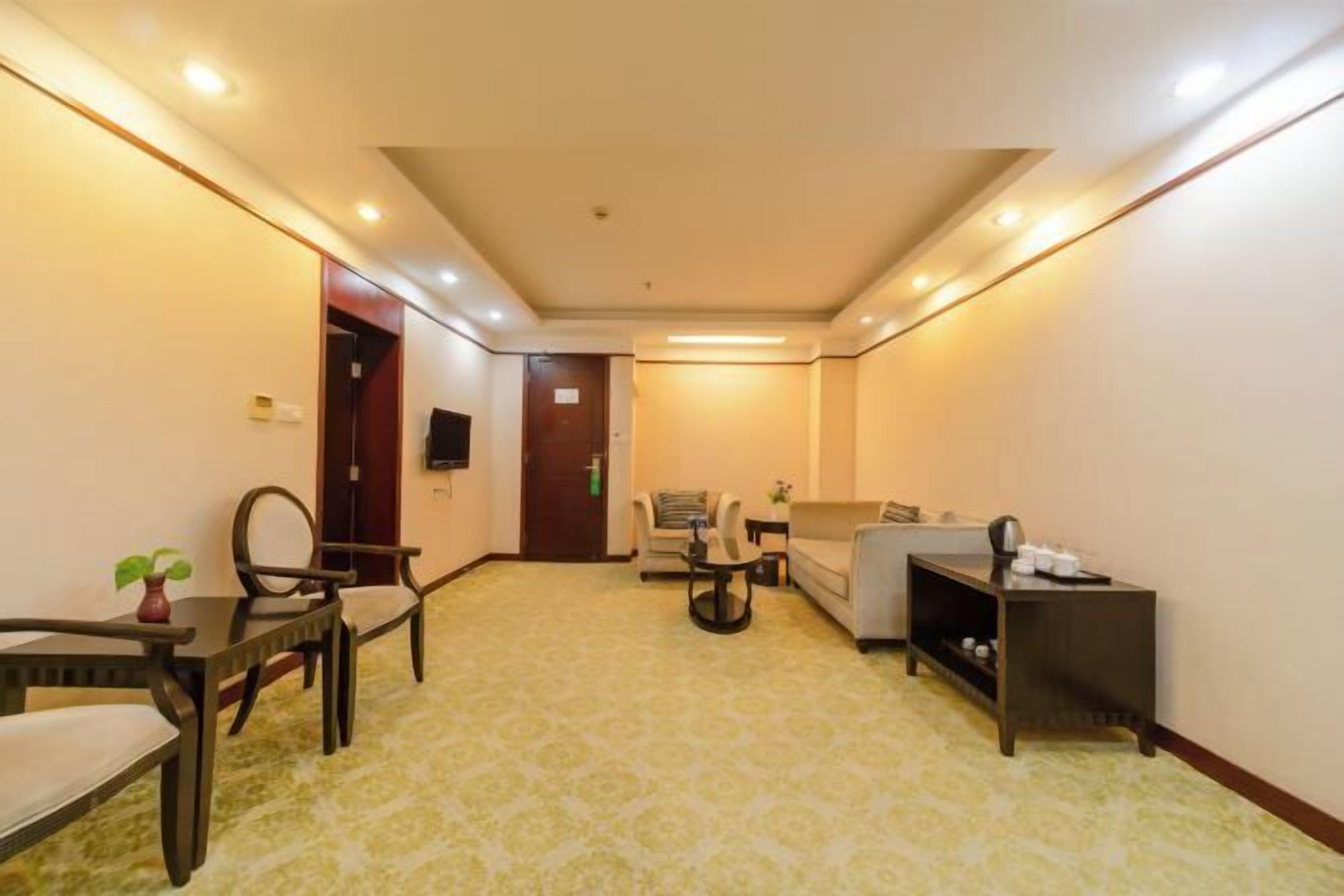 Habitación de hotel con sofá, sillón, mesa de comedor y una mesita auxiliar.