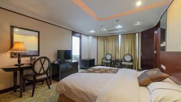 A hotel room with a bed, a desk with a lamp, a television, and a mirror.