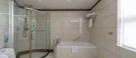 A modern bathroom with a glass-enclosed shower, a standalone bathtub, and a toilet.