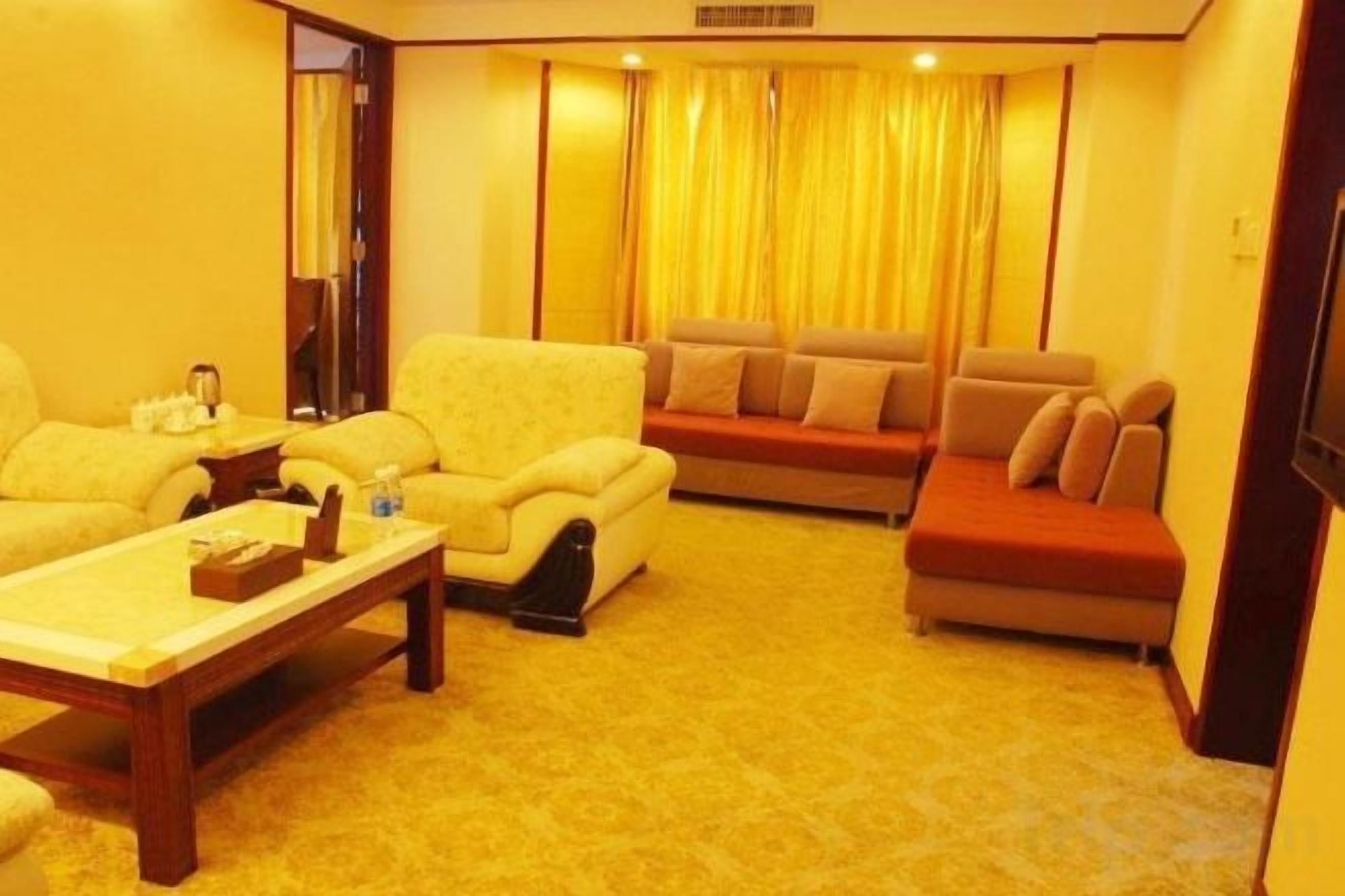 A hotel room with a sofa set, a coffee table, and a television.