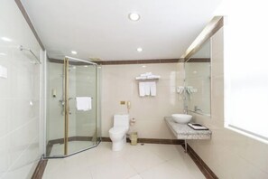 A modern bathroom with a glass-enclosed shower, a toilet, a sink with a marble countertop, and a large mirror. - Kaiping Hotel (Kaiping)