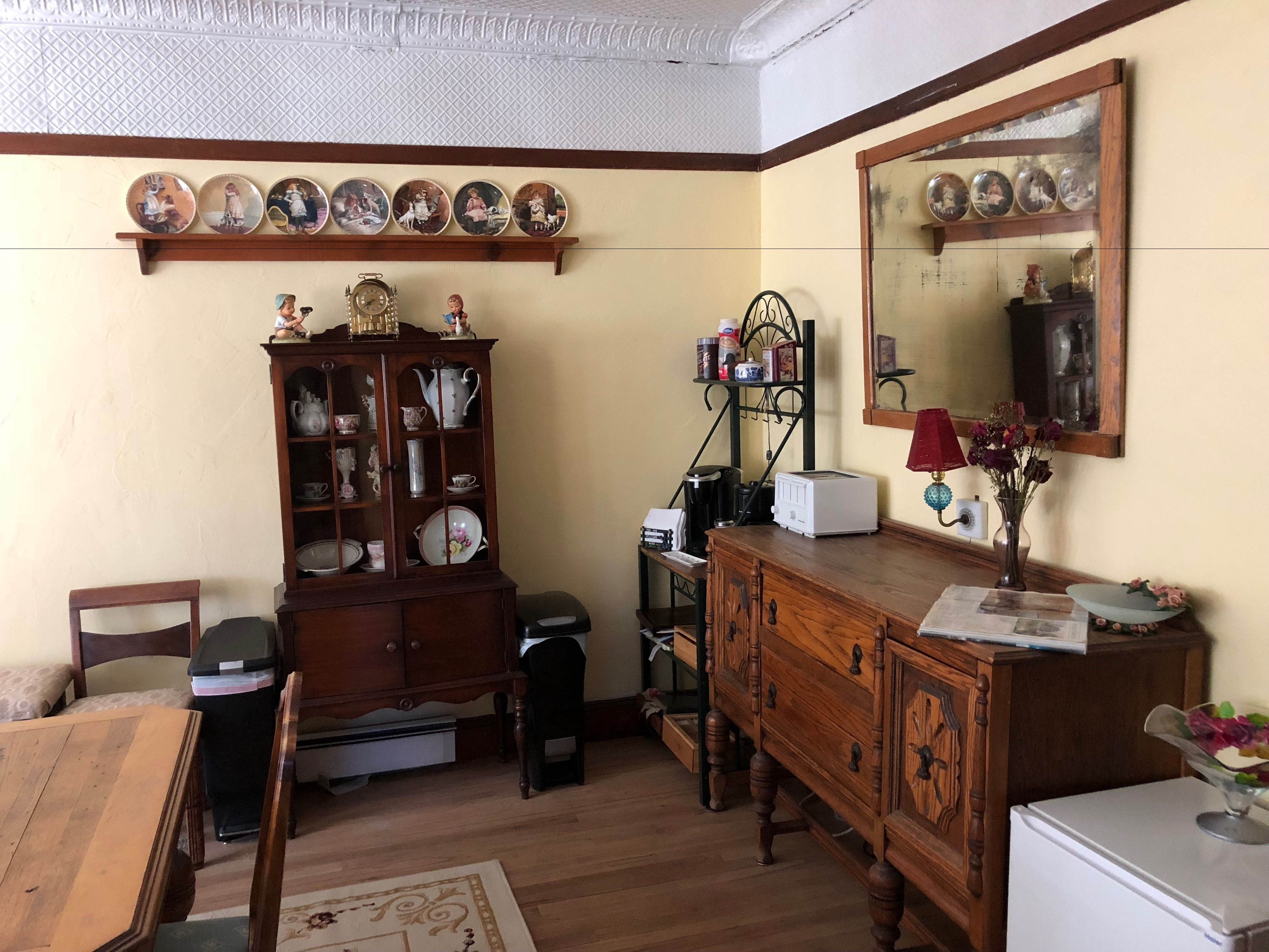 Une pièce comprenant un meuble en bois, un miroir, une horloge et une table à manger avec des chaises.