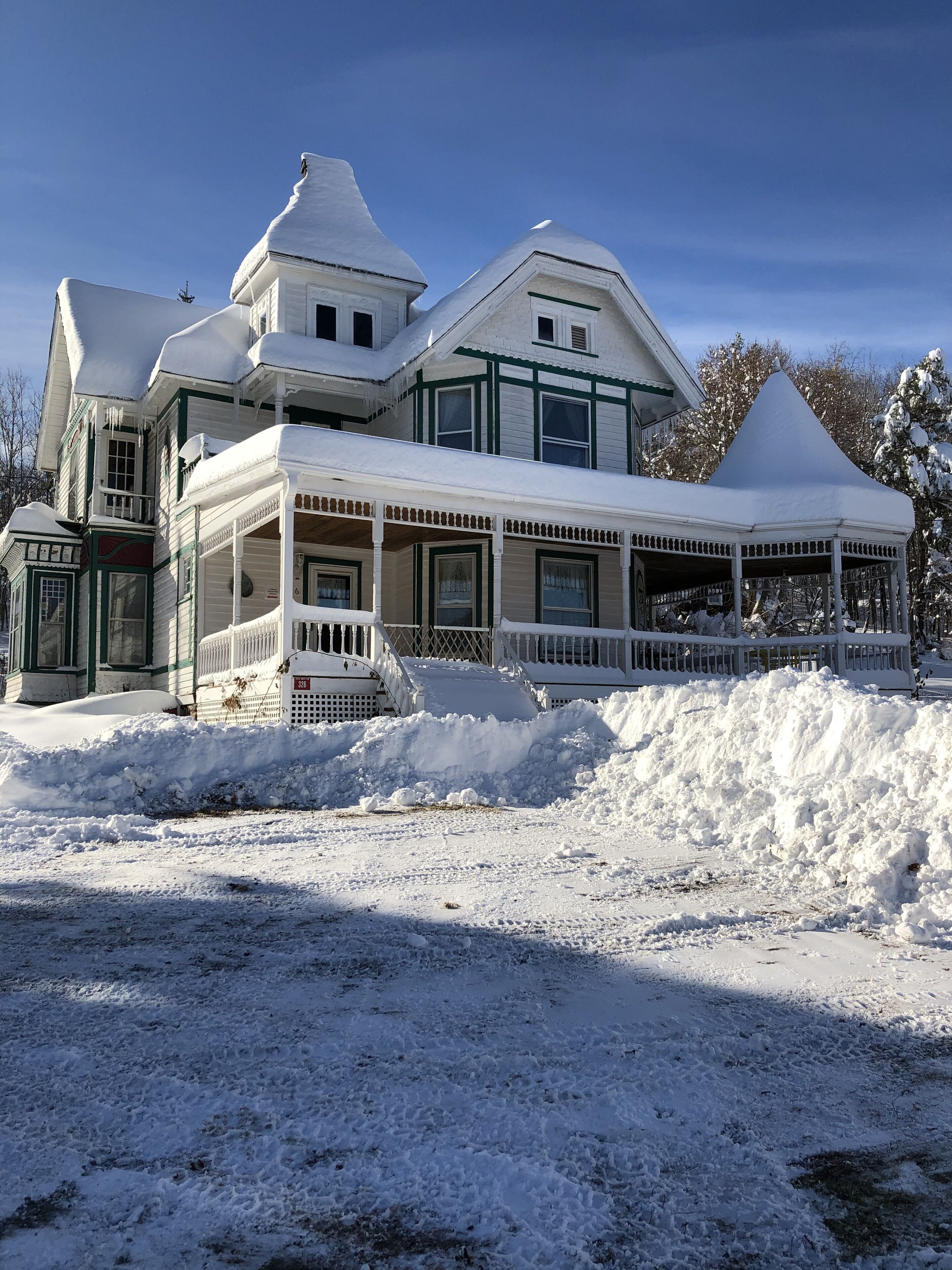Een groot, twee verdiepingen tellend huis met een sneeuwwitte dak en veranda.