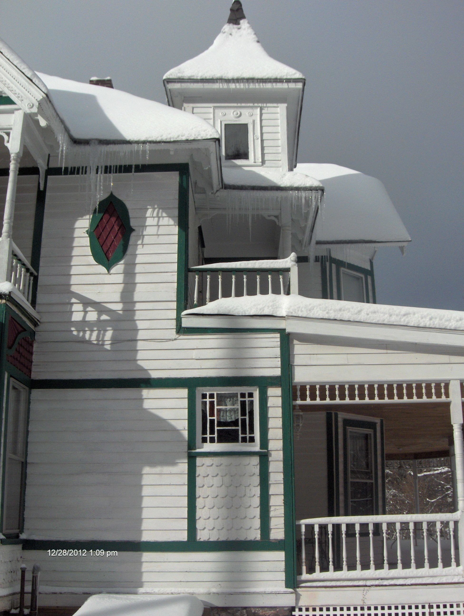 A white building with green trim and a tower.
