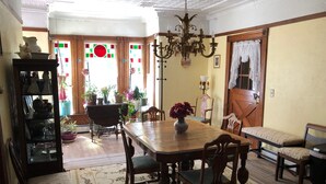 Comedor con mesa de madera, sillas, candelabro y un florero con flores.