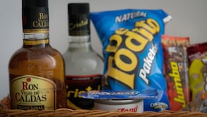 A bottle of Ron Viejo de Caldas, a can of Del Monte, a bag of Natural Iodita chips, and a package of Jumbo chips. - Hotel Portal del Milán (Manizales)