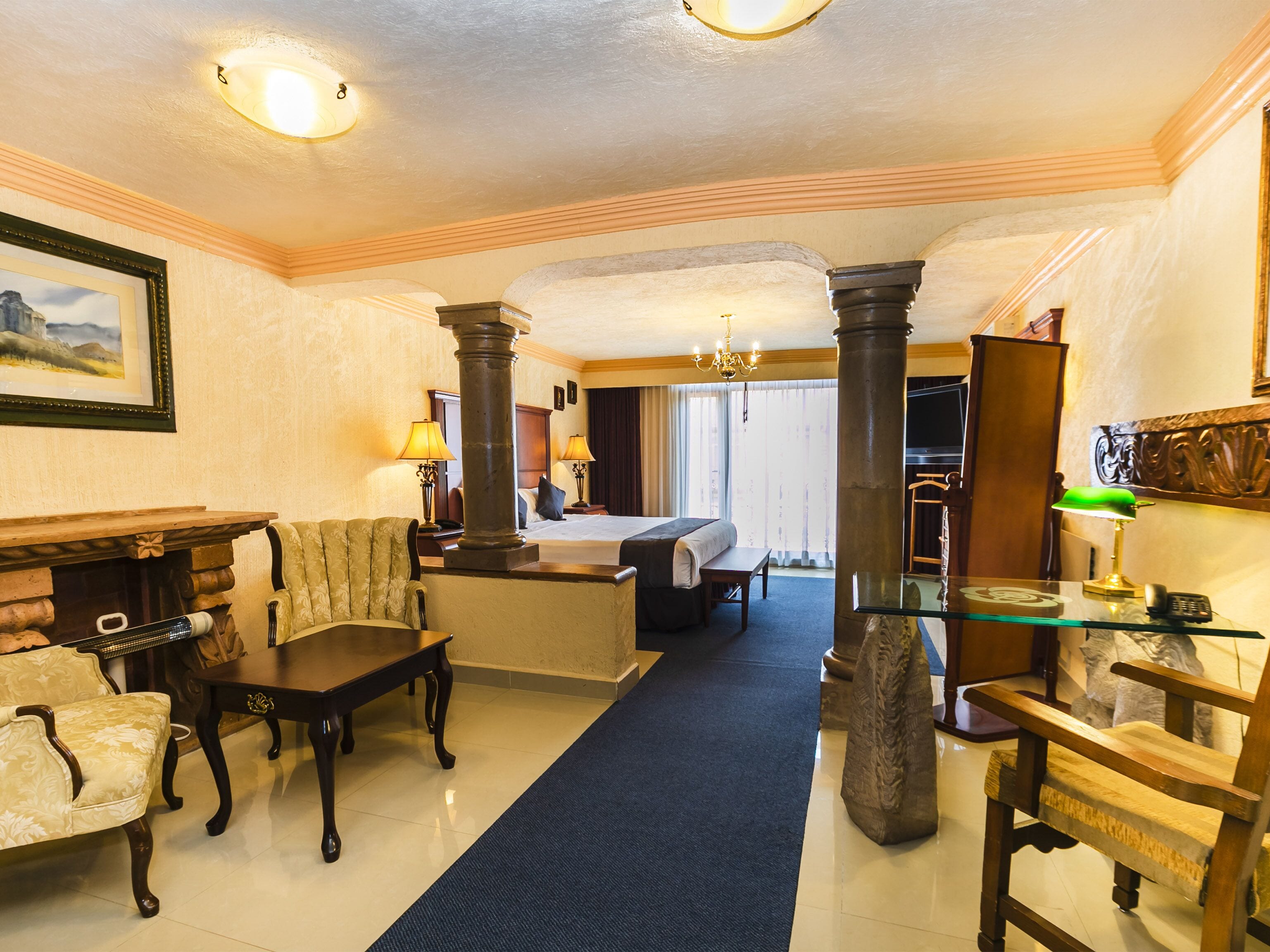 A hotel lobby with a large bed, a fireplace, a chandelier, and a blue carpet.