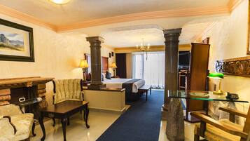 A hotel lobby with a large bed, a fireplace, a chandelier, and a blue carpet.