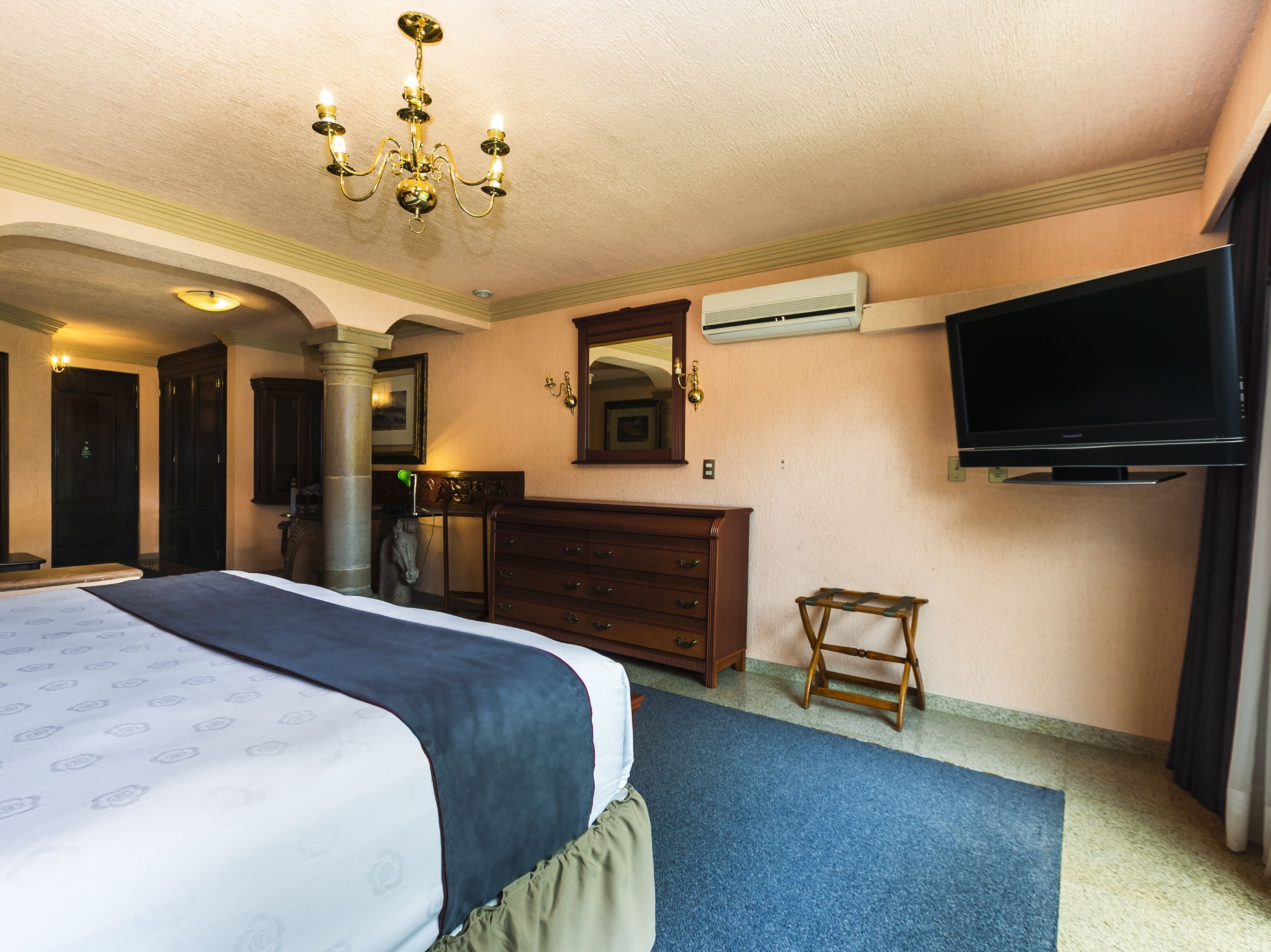 Ett hotellrum med en säng, en byrå, en tv och en luftkonditioneringsanläggning.